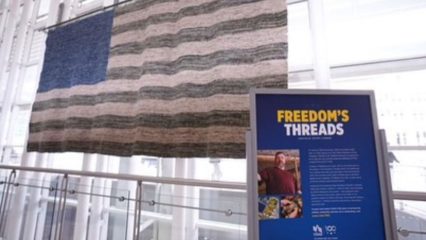 "Freedom's Threads" exhibit beside a quilted flag